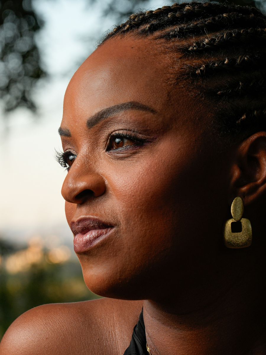 Outdoor portrait of a woman with braided hair and gold earrings at golden hour.