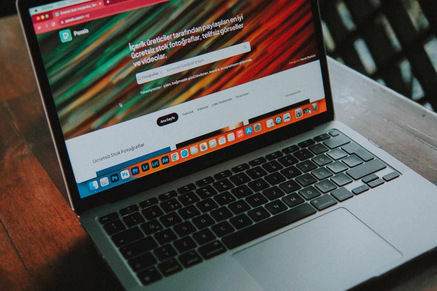 A laptop on a dark table showing a website with a vivid red hero image.